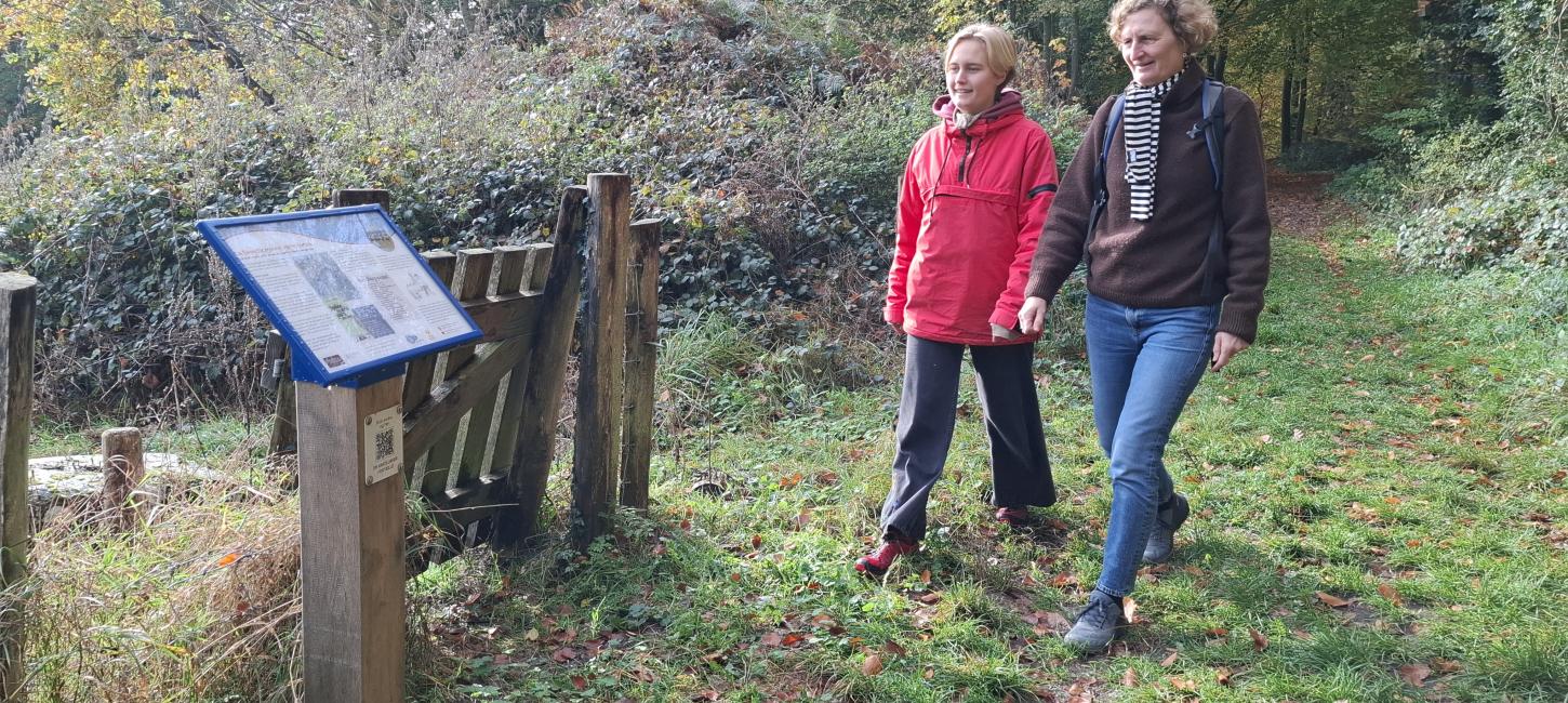 To kvinder læser skilt om vandrefortællinger langs Øhavsstien